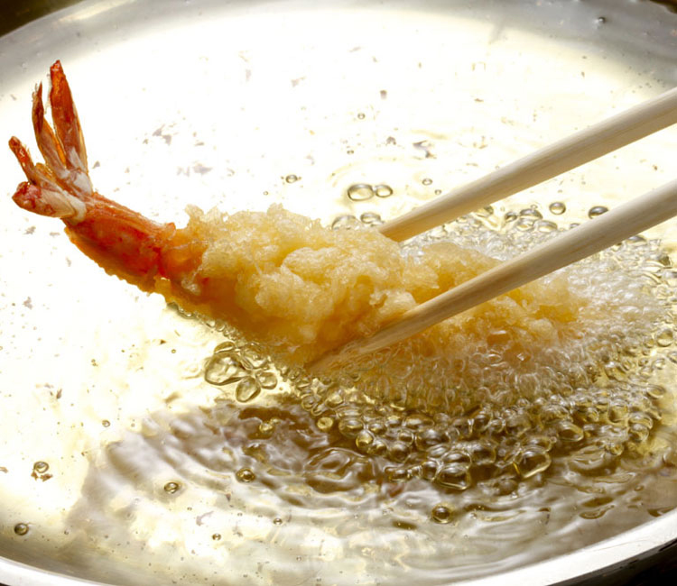 Sumergiendo una gamba en tempura en aceite caliente
