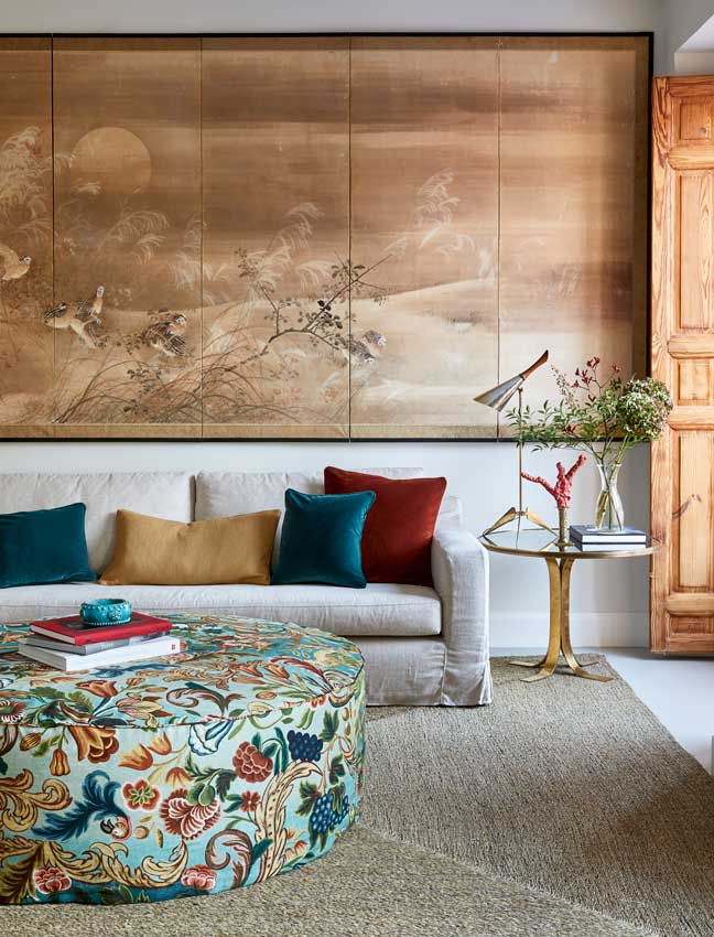 Salón clásico con sofá liso y puf circular de tela estampada