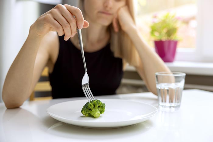 mujer frente a un plato de brócoli